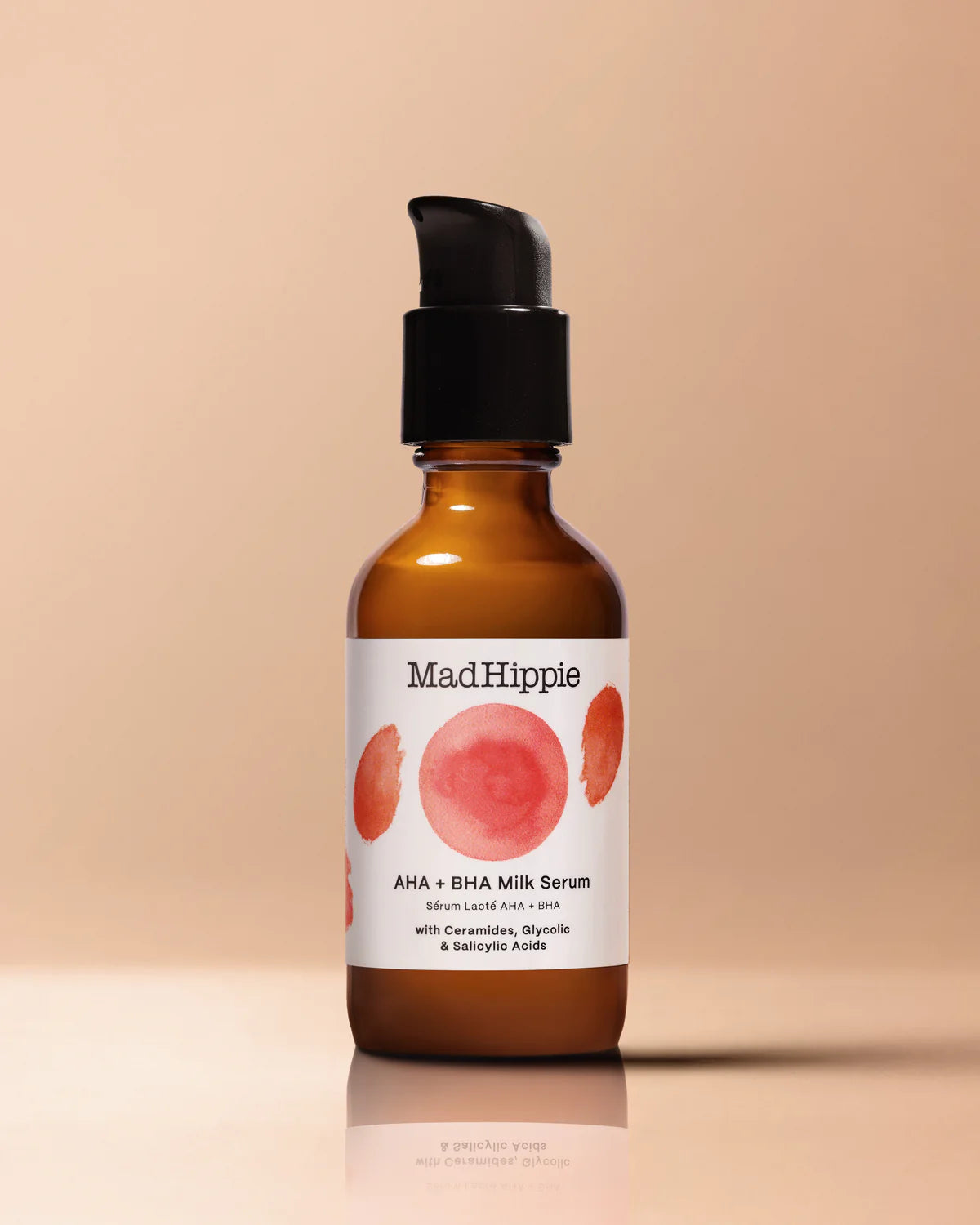 Brown bottle with black pump, labeled "Mad Hippie AHA + BHA Milk Serum" on beige background.